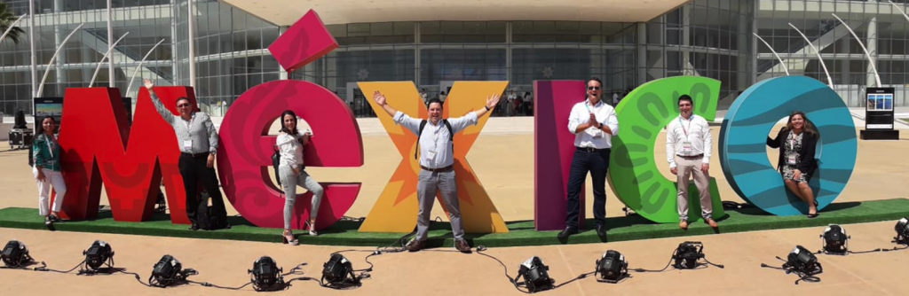 Employees posing in front of MEXICO sign