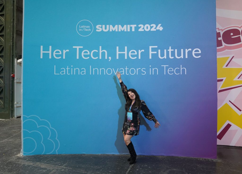 Expedian Veronica in front of Latinas in Tech "Her Tech, Her Future" sign