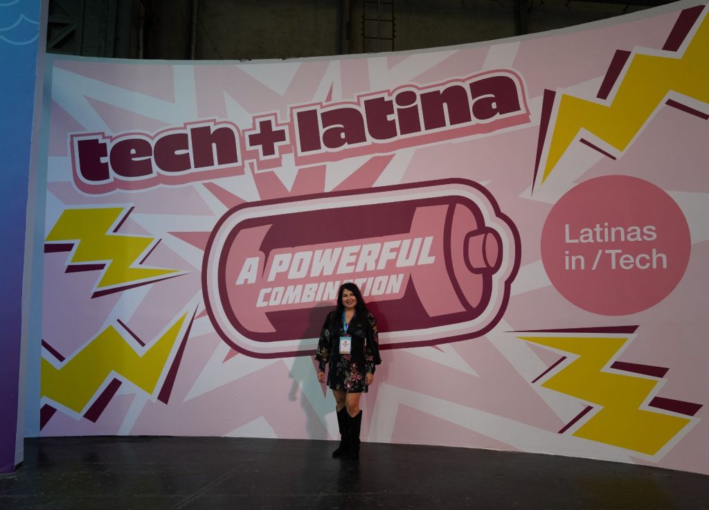 Expedian Veronica in front of Latinas in Tech "tech+Latina a powerful combination" sign